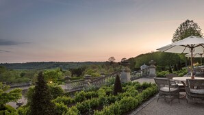 A garden patio with a table and chairs, surrounded by well-manicured hedges and a view of the landscape. - Beaverbrook (Leatherhead)