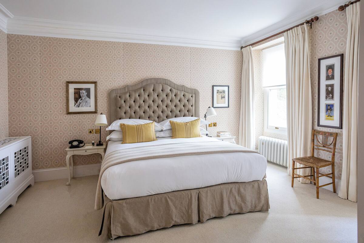 A neatly arranged bedroom with a large bed, bedside tables, a chair, and a radiator.