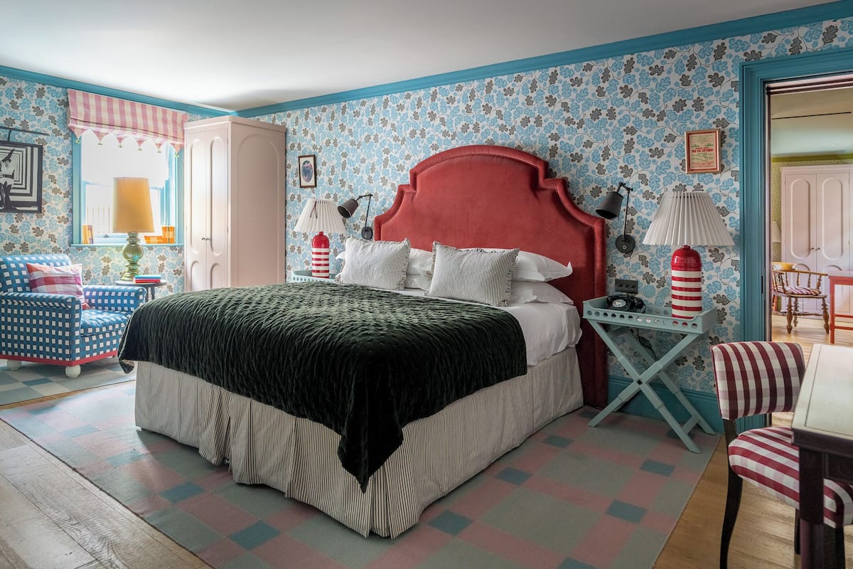A bedroom with a large bed, a wardrobe, a nightstand, a chair, and a small table.