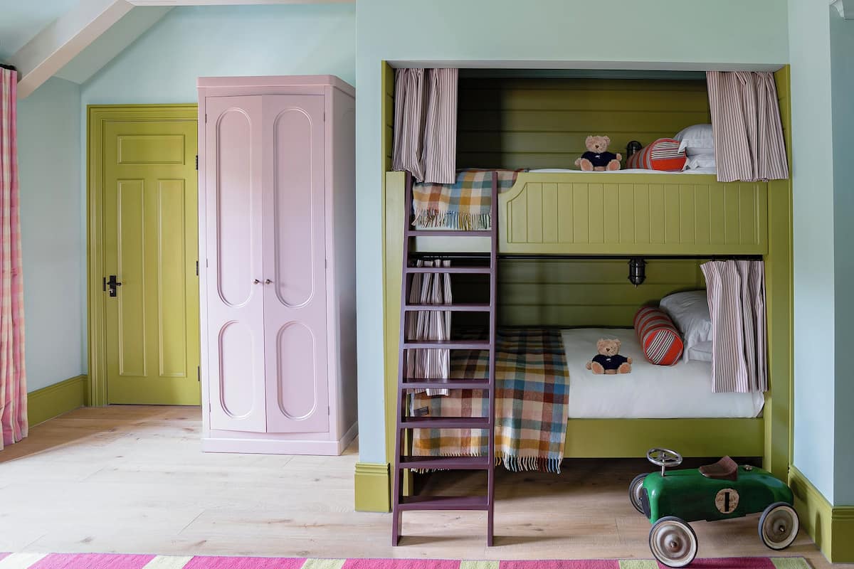 A child's bedroom with bunk beds, a wardrobe, a toy car, and a striped curtain.