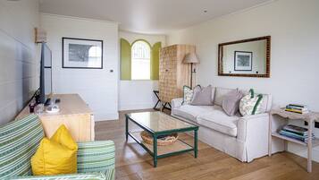 A living room with a sofa, a coffee table, a TV, and a bookshelf.