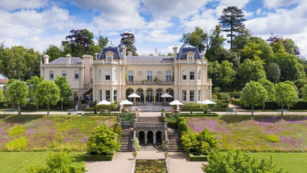 A large, historic building with a symmetrical facade, multiple windows, and a central entrance with steps leading up to it. - Beaverbrook (Leatherhead)