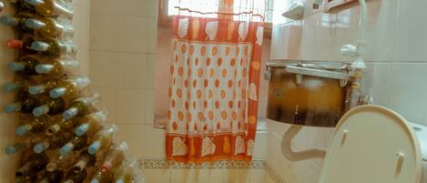 Un baño con inodoro, ducha y lavabo. Hay una cortina con estampado de lunares.