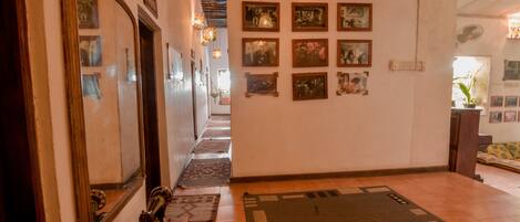 A hallway with a large mirror, patterned rugs, and framed pictures on the wall.