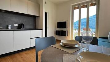 A modern kitchen with a dining area, a flat-screen TV, and a view of the outdoors.