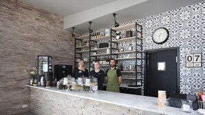 En modern bardisk med en vägg av sten, hyllor med flaskor och en klocka på väggen.