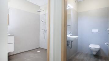 Un baño moderno con ducha, lavamanos e inodoro.