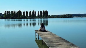 Un muelle de madera que se adentra en aguas tranquilas, con una persona sentada al final.
