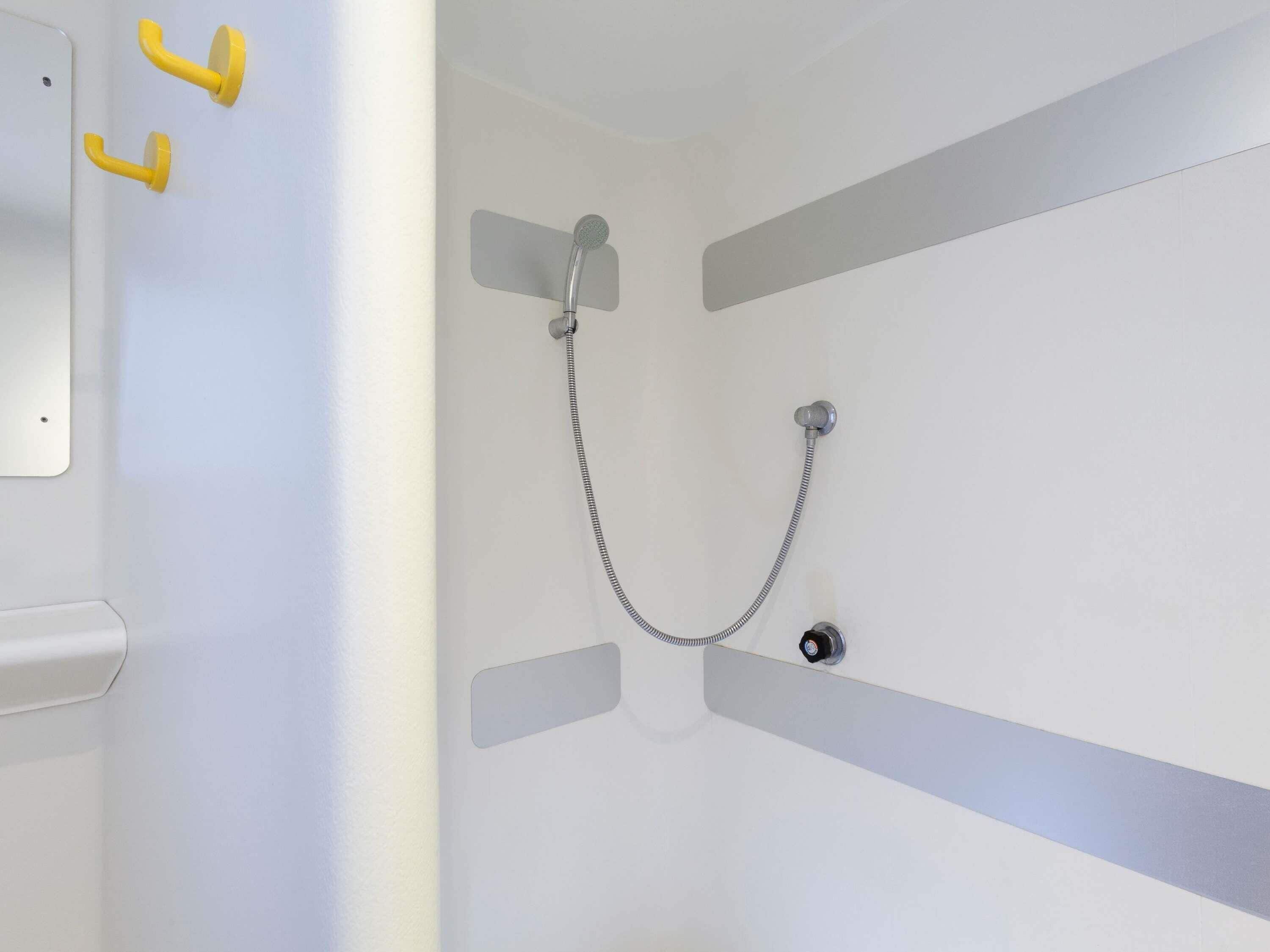 Eine Dusche mit Duschbrause und Armatur an der Wand.