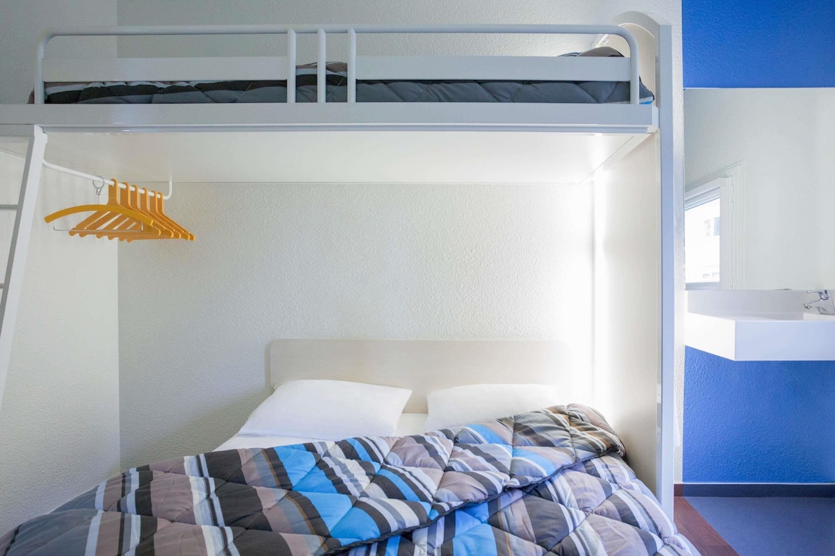 A bunk bed with a white headboard, a hanging yellow clothes rack, and a blue wall.