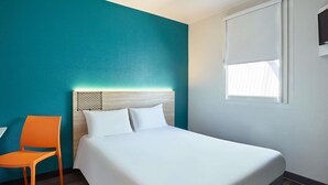 Una habitación de hotel con cama, una silla, un ventanal y paredes color turquesa.