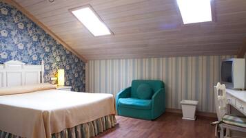 A bedroom with a bed, a chair, a desk, and a television.