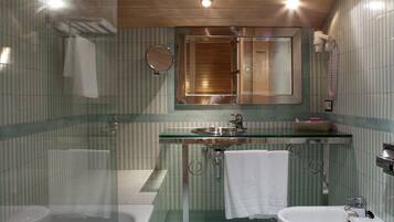 Une salle de bain avec une douche à parois de verre, un lavabo avec un miroir au-dessus et des toilettes.