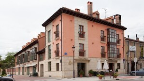 A hotel with a pink facade, multiple balconies, and outdoor seating. - Hotel Azofra (Burgos)