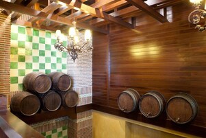 Una bodega con barricas de madera y un muro a cuadros.