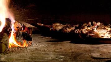 A traditional open fire cooking area with various meats being roasted.