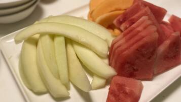 Un plato con rodajas de manzana y sandía, rodeado de otras frutas y un cuchillo.