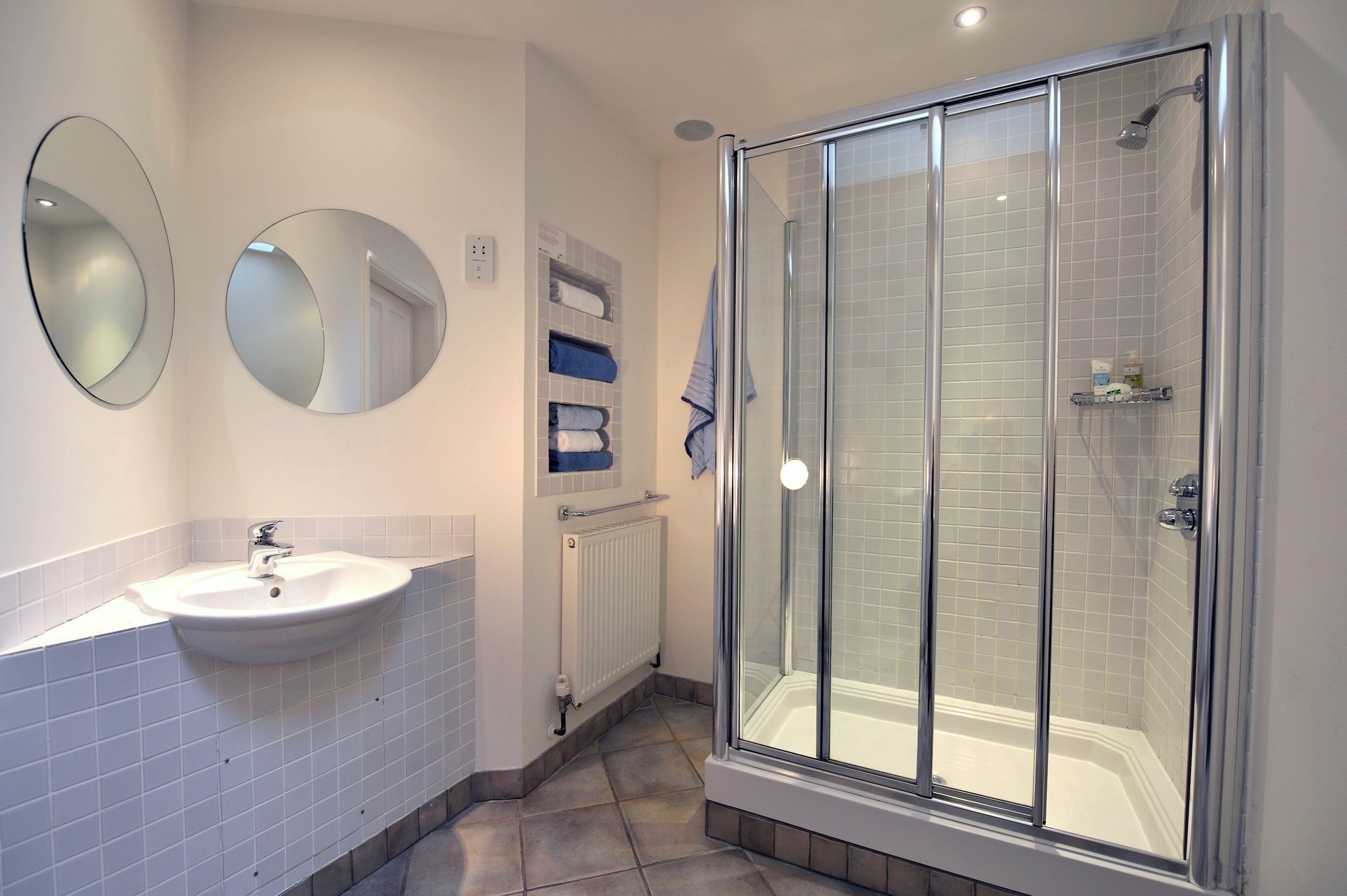 A bathroom with a white sink, a mirror, a glass-enclosed shower, and a towel rack.