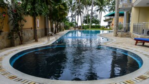 A swimming pool with a curved edge, surrounded by a stone border and a tiled deck. - Lido Beach Resort (Mombasa)