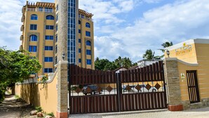 A multi-story building with a distinctive cylindrical tower, a gated entrance, and a sign indicating it is a beach resort. - Lido Beach Resort (Mombasa)
