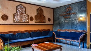 A lobby with a blue sofa, a wooden coffee table, and decorative wall panels. - Lido Beach Resort (Mombasa)