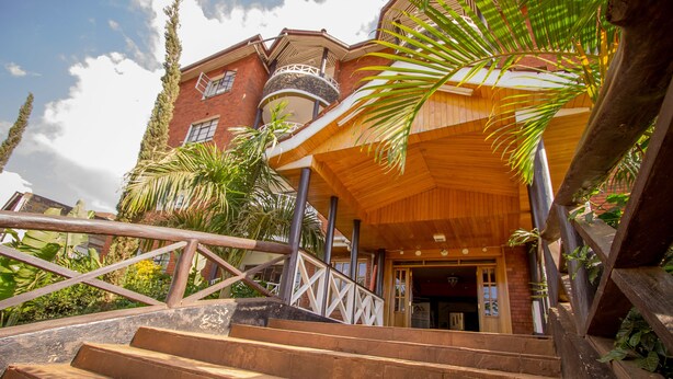 A multi-level building with a wooden staircase leading to a covered entrance. - Magharibi Garden Hotel (Kisii)