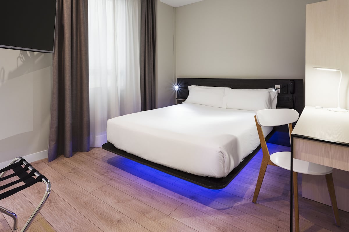 Een moderne hotelkamer met een groot bed, een bureau en een stoel.