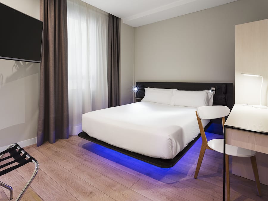Una habitación de hotel moderna con cama, escritorio y silla.
