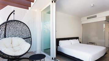 Una habitación de hotel moderna con una cama grande, un sillón colgante y una mesita.