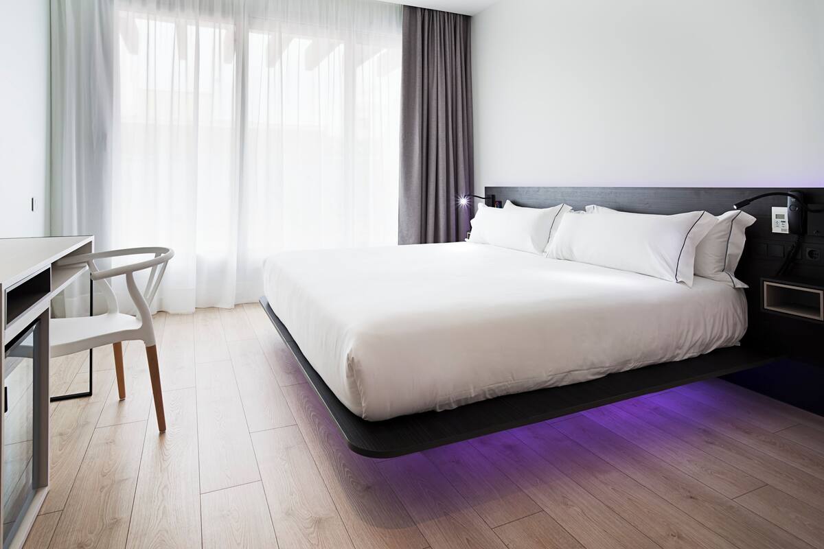 Een moderne hotelkamer met een groot bed, een bureau en een stoel.
