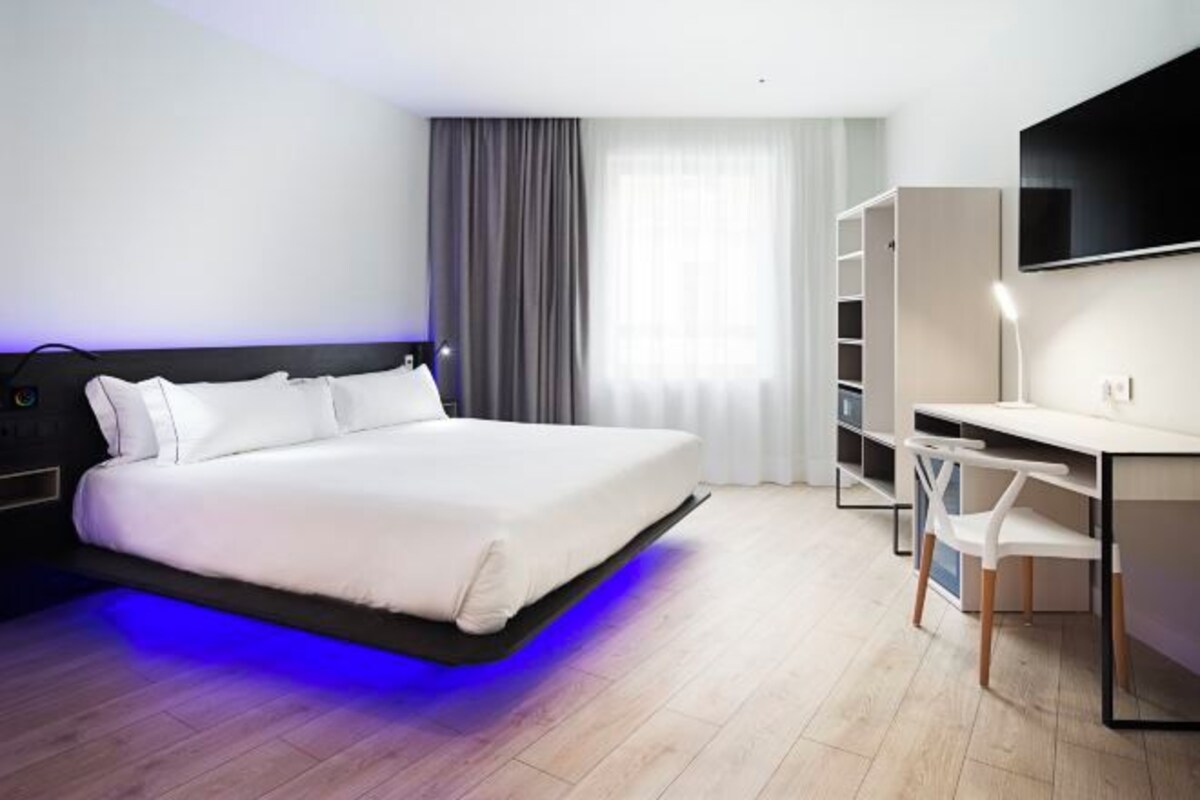 Une chambre d’hôtel moderne équipée d’un lit, d’un bureau et d’une télévision.