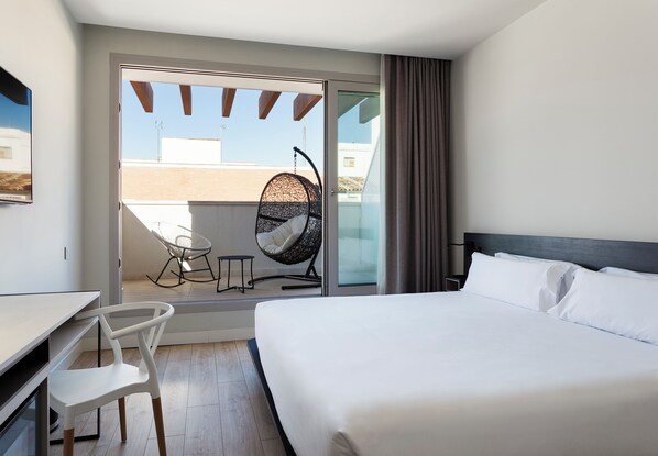 Een hotelkamer met een bed, een bureau, een stoel en een balkon met een hangstoel.