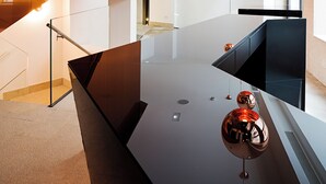 Eine moderne Küche mit einer glatten schwarzen Arbeitsplatte, Kupfer-Pendelleuchten und Holzschränken.
