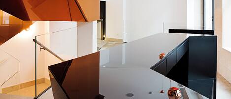 A modern kitchen with a sleek black countertop, copper pendant lights, and wooden cabinetry.