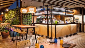 Ein Essbereich im Freien mit einer Bar, Korbstühlen, einem Holztisch und Geschirr sowie Besteck.