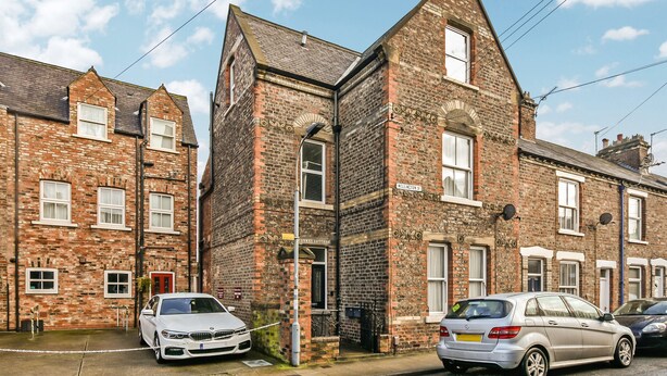 A row of terraced houses with brick facades, a white car parked in front, and a street sign indicating the name of the street. - Conway Cottages (York)
