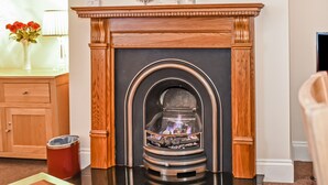 A fireplace with a modern design, a wooden mantel, and a glass enclosure. - Conway Cottages (York)
