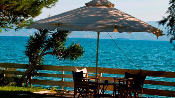 A wooden deck with a table and chairs, overlooking a body of water. - Villa Aggeliki (Eretria)
