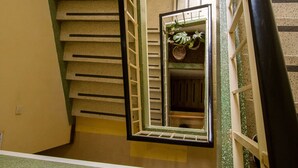 A spiral staircase with a mirrored wall, a small plant, and a decorative item on the landing. - Meru Safari Hotel (Meru)