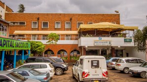 A parking lot with several cars, a building with a sign for 'Capital Sacco Ltd' and 'Meru Safari Hotel'. - Meru Safari Hotel (Meru)