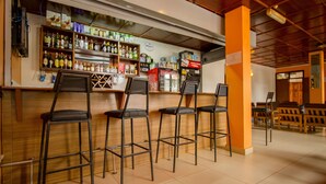 A bar area with stools, shelves of bottles, and a refrigerator. - Meru Safari Hotel (Meru)