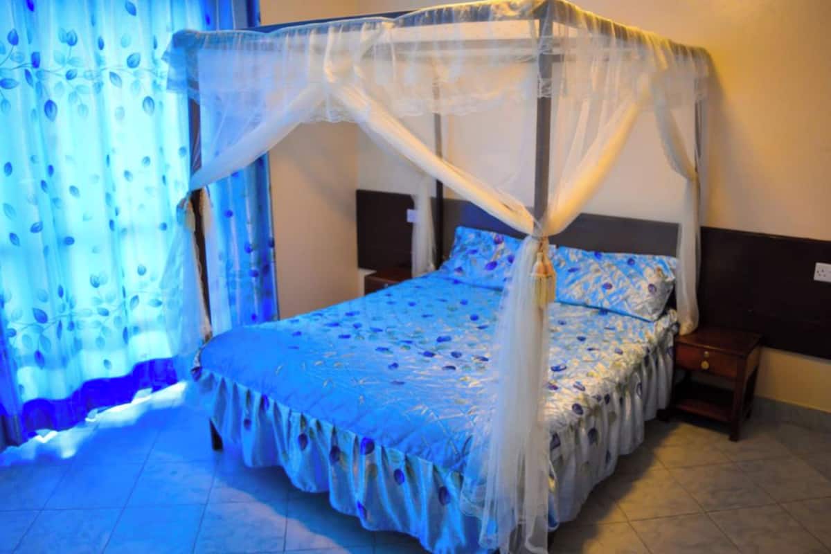 Een hemelbed met hemel, nachtkastje en nachttafel.
