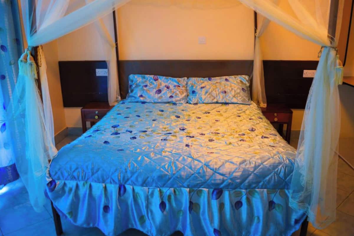 Een bed met hemel, hoofdeinde en nachtkastje.