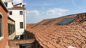 A rooftop with terracotta tiles, a small courtyard with a metal railing, and a building with a white facade and a satellite dish. - Harry's Guest House (Venice)