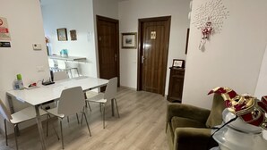 A dining area with a white table and chairs, a wooden floor, and a green armchair. - Harry's Guest House (Venice)