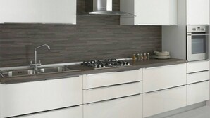 A modern kitchen with white cabinets, a stainless steel sink, a gas stove, and a built-in oven. - Harry's Guest House (Venice)