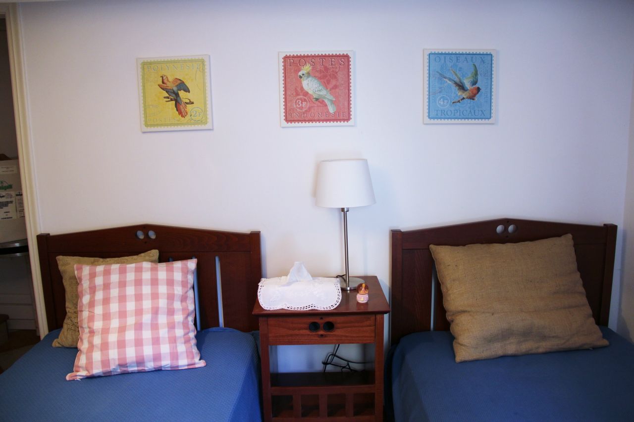 A room with two beds, each with a distinct pillow and a bedside table with a lamp.