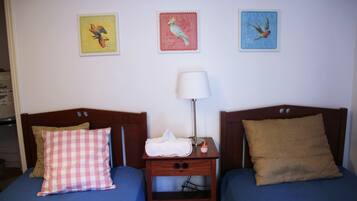 A room with two beds, each with a distinct pillow and a bedside table with a lamp.