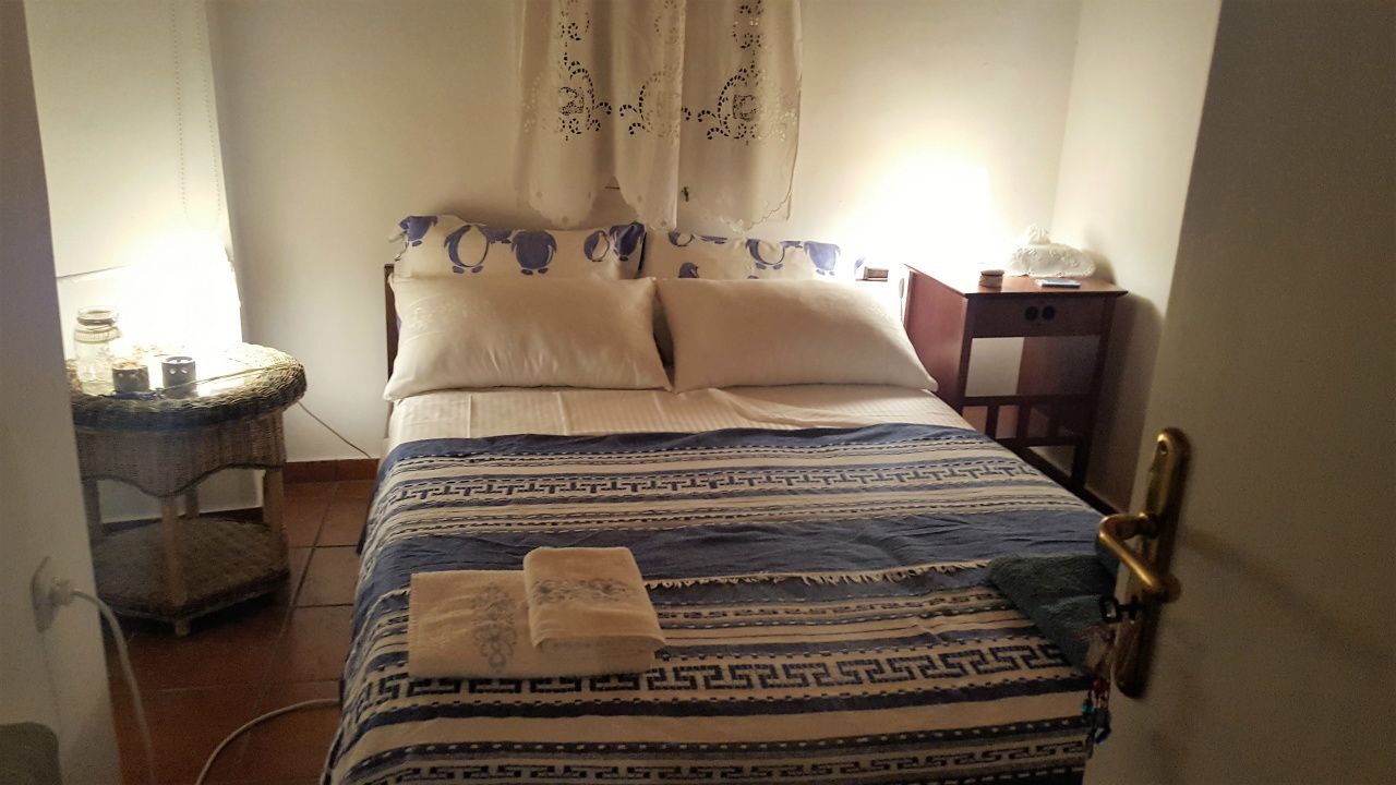 Un dormitorio con cama, almohadas, mesita de noche y velador.