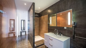 Un baño moderno con cabina de ducha, un espejo grande y un tocador blanco.